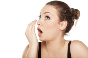 young woman checking her breath with her hand